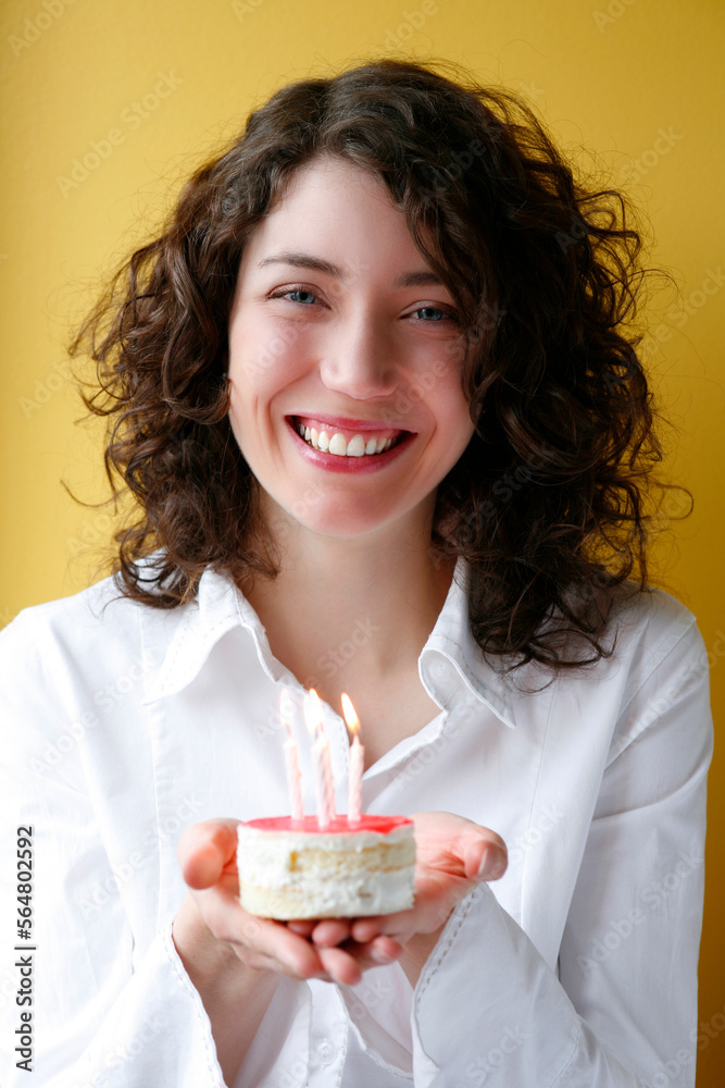 Close up of attractive young woman showing small birthday cake with candles. Close up of attractive young woman showing small birthday cake with candles.
