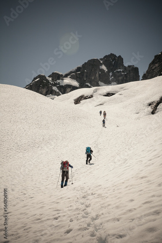 Six climbers cross a snow patch en route to climb Trio Peak in British Columbia, Canada.