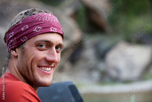 A portrait of a man smiling while looking into the camera with a bandanna on. photo