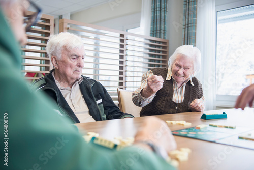 Senior inhabitants playing board game in rest home photo