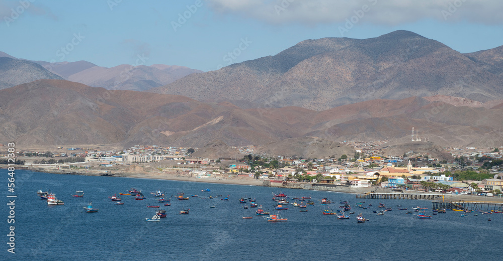 view of a town with boats in the bay and mountains