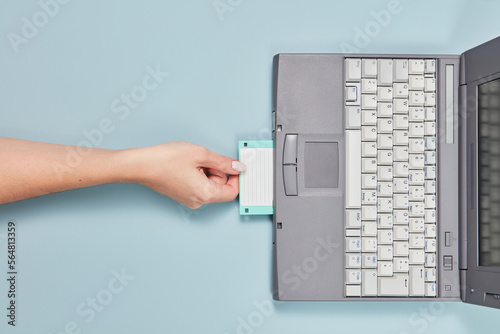 90s laptop with hand put floppy disk inside. photo