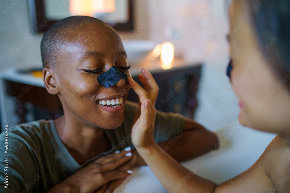 Woman applying nose strip on friend at home Woman applying nose strip on friend at home
