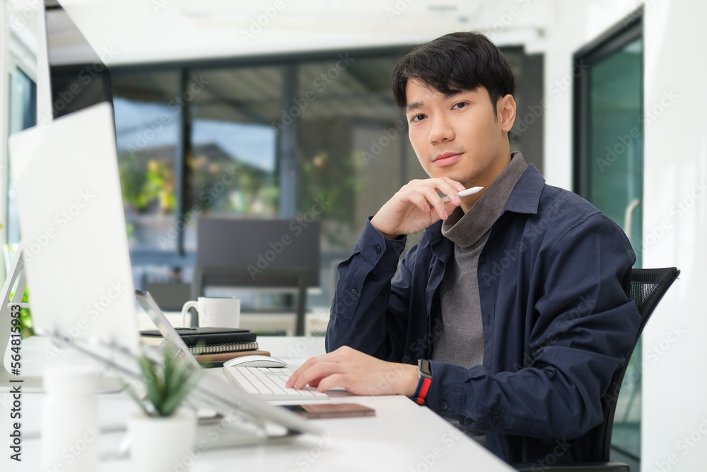 Portrait of young start up businessman sitting front of computer in his office and looking at camera. Portrait of young start up businessman sitting front of computer in his office and looking at camera.