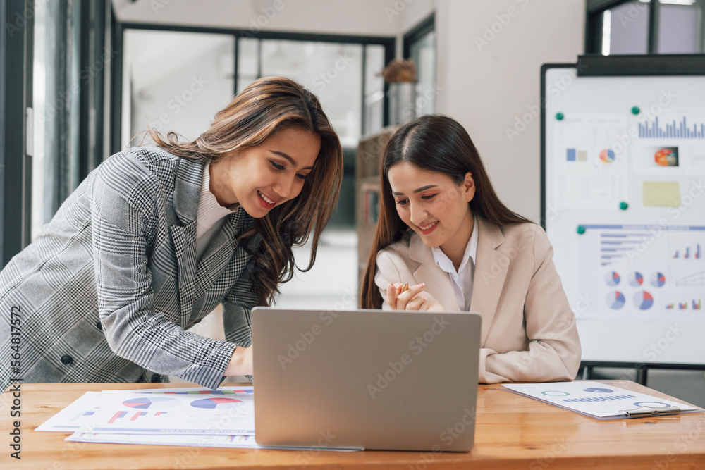 Two young pretty asia business woman in suit talking together in modern office workplace, Thai woman, southeast asian, looking on laptop together Two young pretty asia business woman in suit talking together in modern office workplace, Thai woman, southeast asian, looking on laptop together