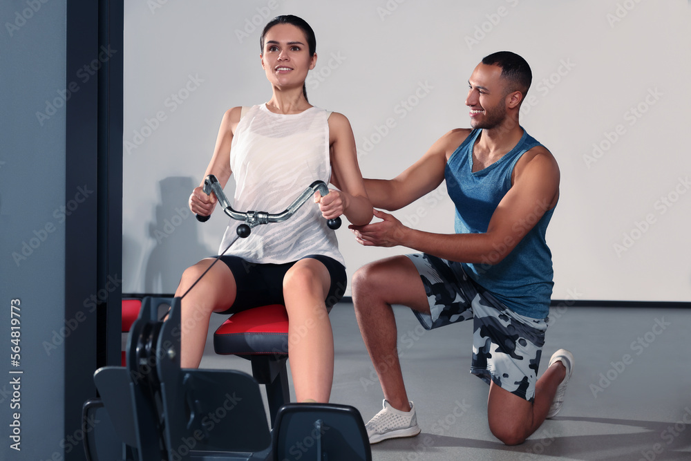Happy trainer explaining woman how to do exercise properly in modern gym Happy trainer explaining woman how to do exercise properly in modern gym