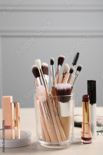Set of professional brushes and makeup products on wooden table indoors