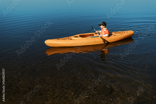 Little boy in a kayak alone and paddling independently on a lake photo