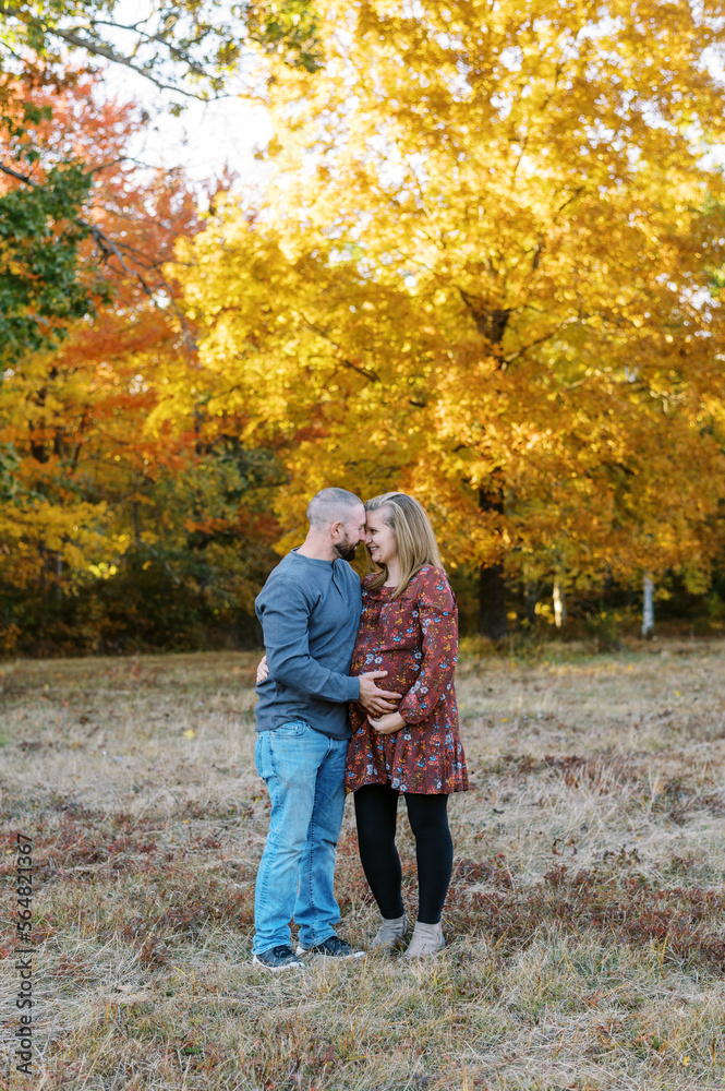 man and pregnant woman hugging outdoors in fall man and pregnant woman hugging outdoors in fall