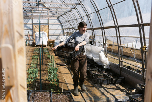 small business woman holding crate while in her hoop house