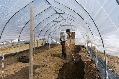 Flower Farmer preparing rows in spring time for planting in greenhouse photo