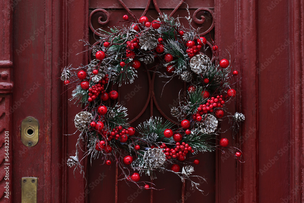 Beautiful Christmas wreath hanging on red door Beautiful Christmas wreath hanging on red door