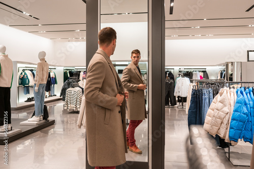 Man Trying On Coat At Clothing Store photo