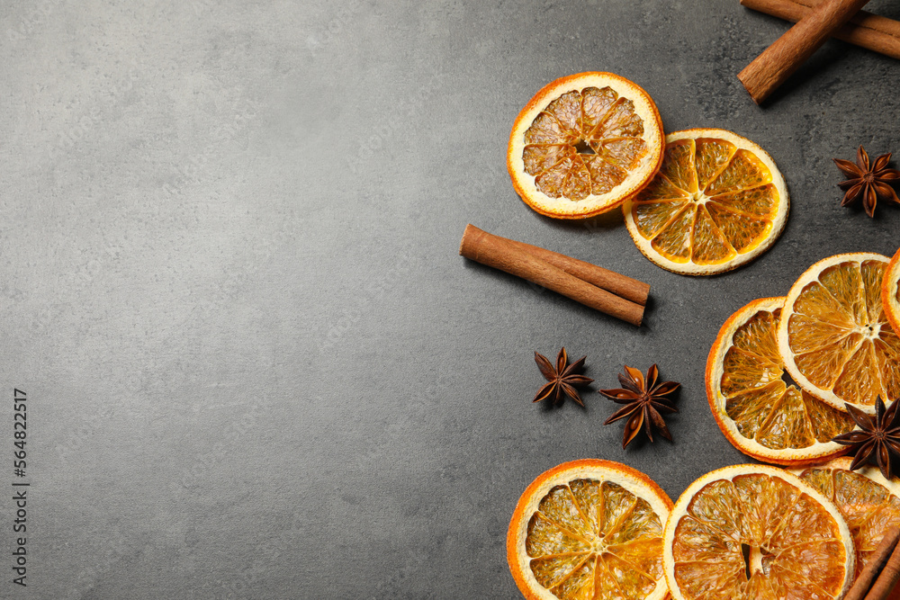 Fototapeta premium Dry orange slices, cinnamon sticks and anise stars on black table, space for text