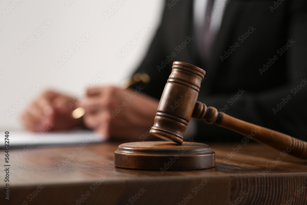 Law and justice. Closeup of judge working at wooden table, focus on gavel