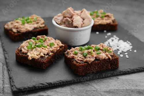 Tasty sandwiches with cod liver  salt and green onion on light grey table