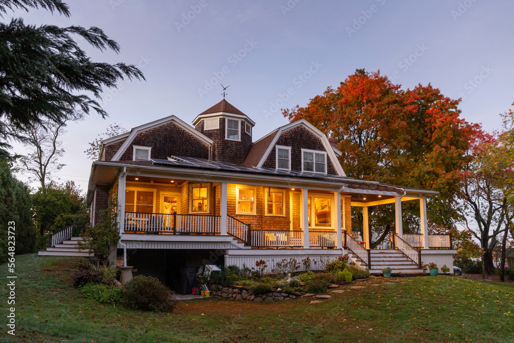 Exterior of Craftsman home with porch in fall at sunset with woman Exterior of Craftsman home with porch in fall at sunset with woman