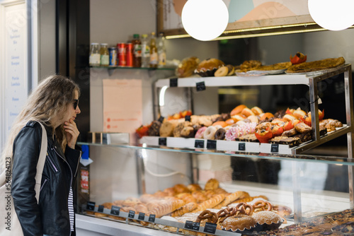 Woman looks at showcase with colorful cakes  photo