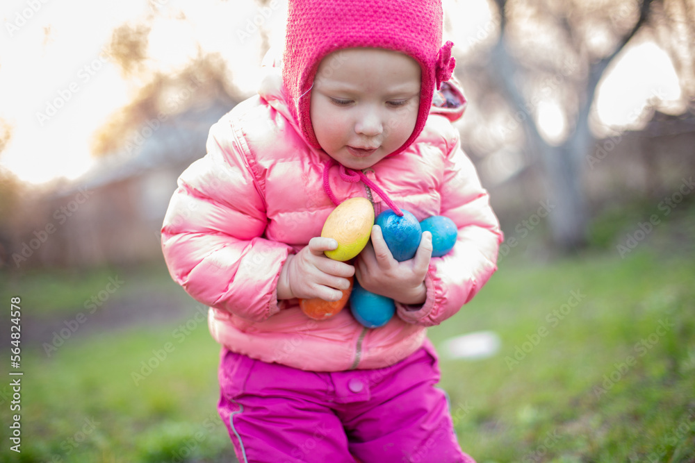 A little girl holds many of the Easter eggs found in her hands. Easter Day. Easter egg hunt concept A little girl holds many of the Easter eggs found in her hands. Easter Day. Easter egg hunt concept