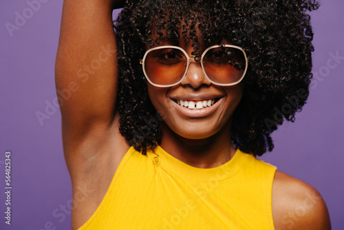 Cheerful black woman in trendy sunglasses showing her shaved armpit