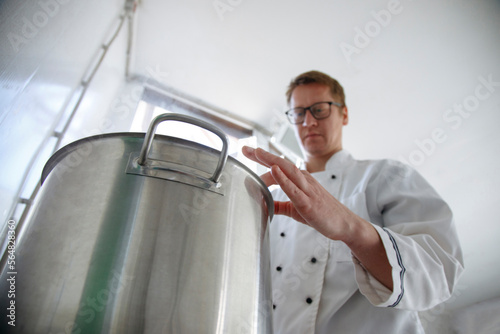 Worker cook cheese in a saucepan in a cheese factory photo