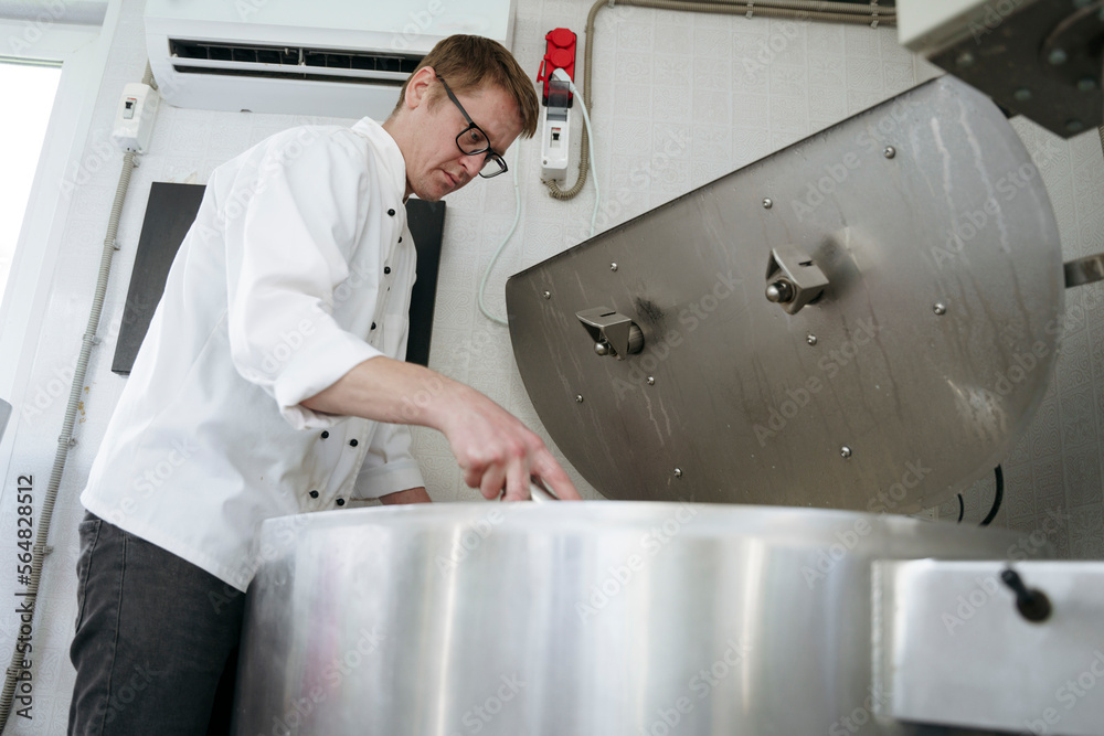 A worker is stirring cheese in a cheese factory A worker is stirring cheese in a cheese factory