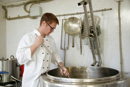 A worker at a cheese factory cuts cheese in a pasteurizer photo