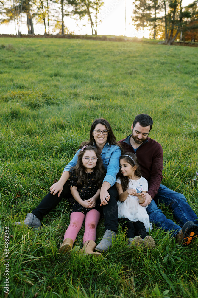 Family hugging and sitting in grass at sunset Family hugging and sitting in grass at sunset