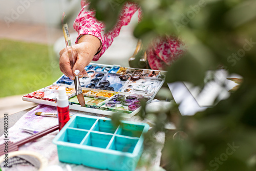 Woman hand with artistic painting skills taking pigment with brush