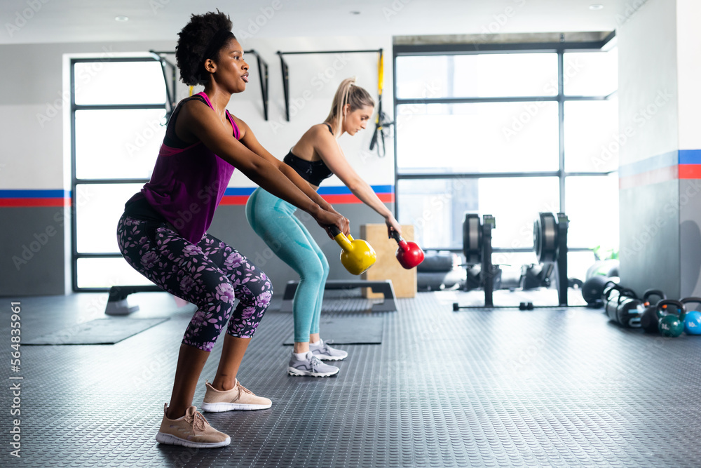 Diverse fit women exercising and using kettlebells at a gym Diverse fit women exercising and using kettlebells at a gym