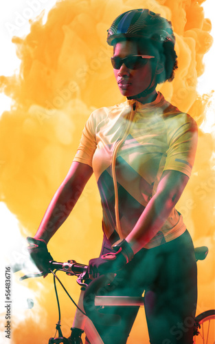 Confident african american cyclist wearing helmet and glasses standing with bike on smoky background