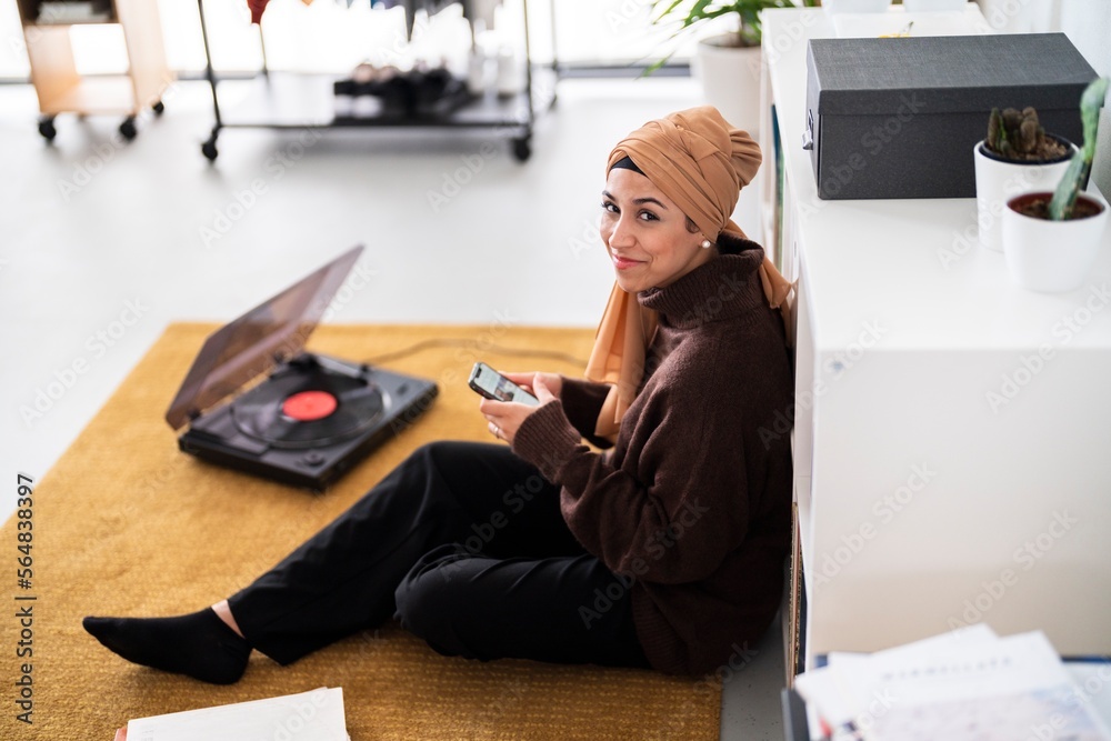 Muslim music lover using smartphone on floor Muslim music lover using smartphone on floor