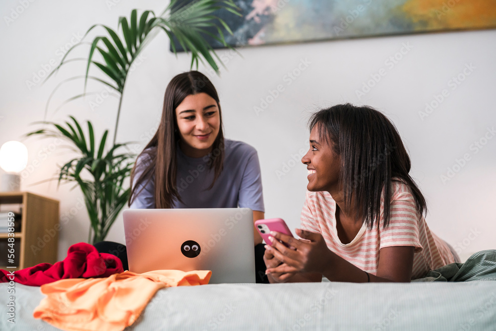 Content diverse women resting on bed with netbook