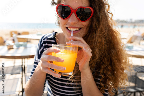 Trendy joyful woman drinking juice at beach restaurant