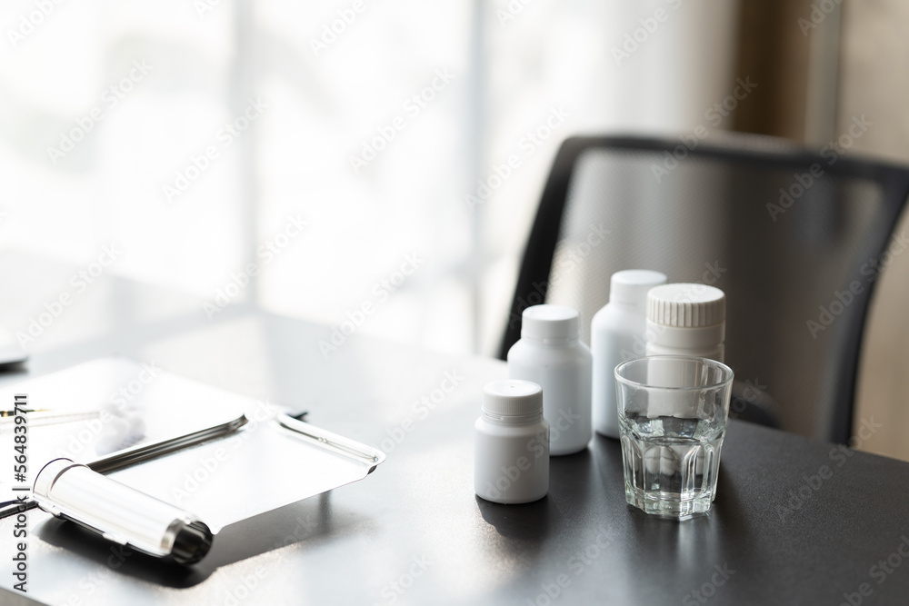 Doctor's workplace with bottle of different pills on the table.