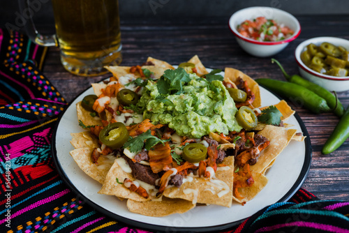Mexican Nachos with cheese or tortilla chips with meat, avocado and beer, tex mex food in Mexico America