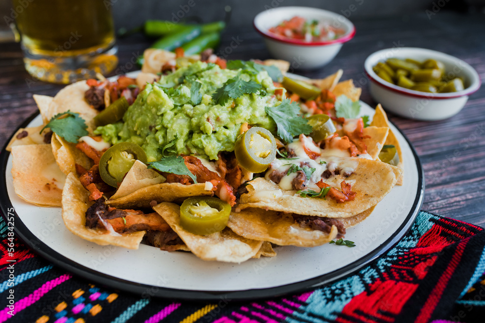 Mexican Nachos with cheese or tortilla chips with meat, avocado and beer, tex mex food in Mexico America Mexican Nachos with cheese or tortilla chips with meat, avocado and beer, tex mex food in Mexico America