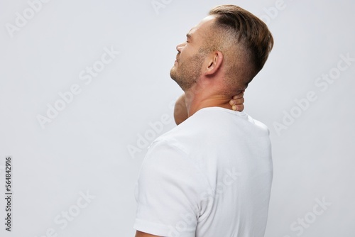 Man back pain neck and joints, bone and spine problems, inflammation and trauma, in white T-shirt on white isolated background, copy space