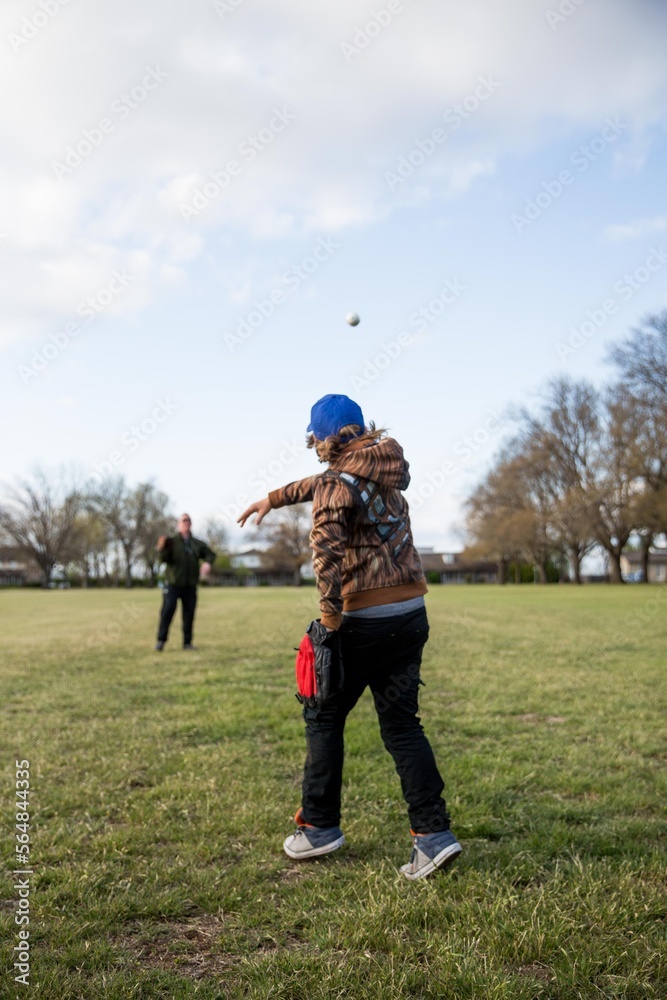 Father and son playing catch in a field in a neighborhood Father and son playing catch in a field in a neighborhood