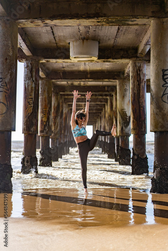 Happy woman dancing under the pier, above the water at the beach