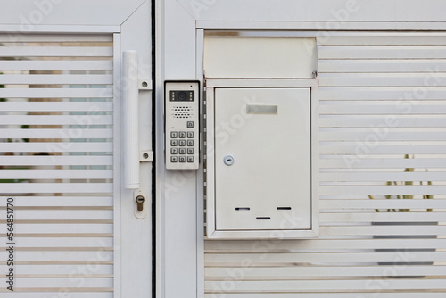 Modern intercom on white door © Pixel-Shot