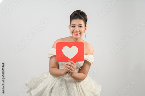 Asian beautiful bride smiling and posing with heart sign on white background