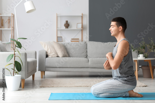 Young man meditating on mat...