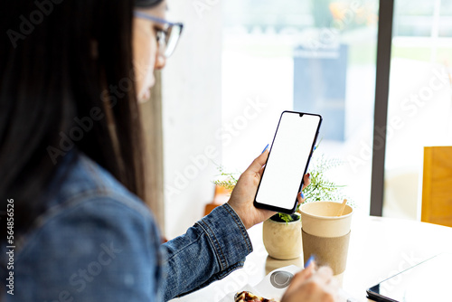 Young woman using smartphone to surf internet while having breakfast photo