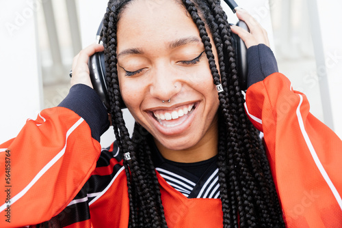 self-confident and expressive woman with long braids listening music photo