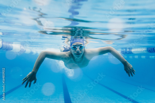 latin young teenager man swimmer athlete wearing cap and goggles in a swimming underwater training In the Pool in Mexico Latin America 