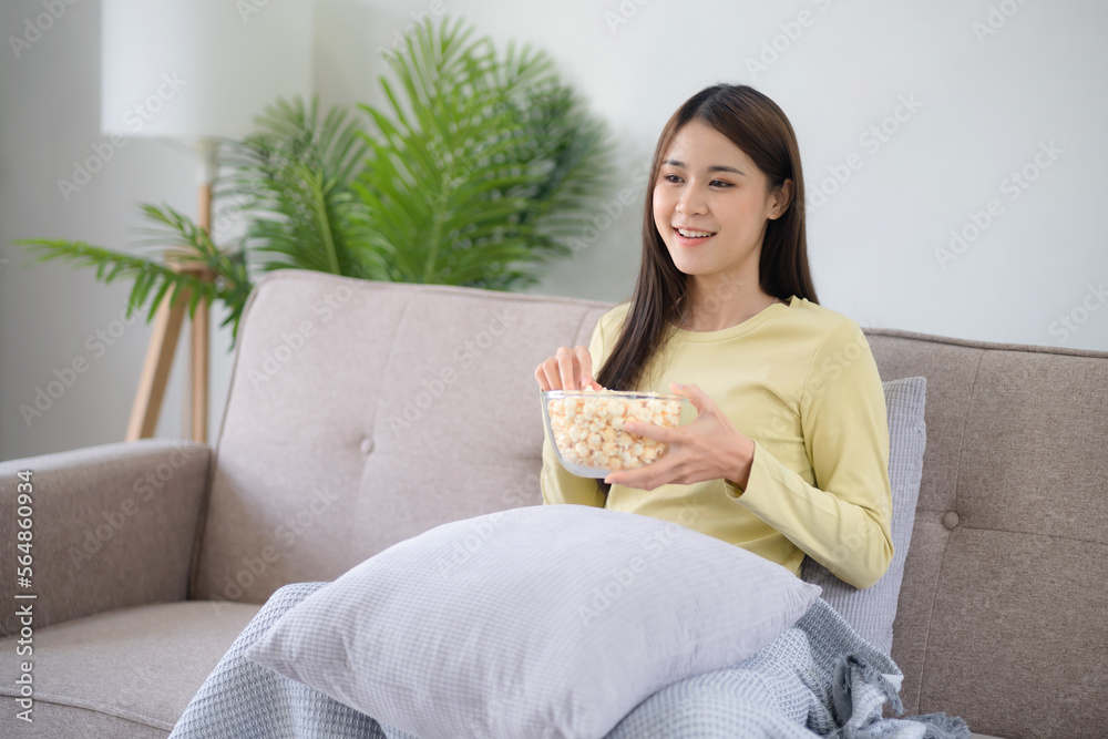 Asian girl relaxing at home Enjoying Watching Television with glass bowl of popcorn Asian girl relaxing at home Enjoying Watching Television with glass bowl of popcorn