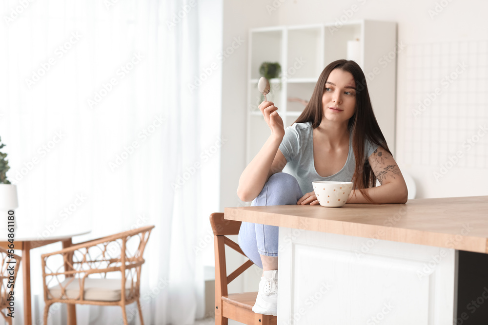 Young woman having breakfast at table in kitchen Young woman having breakfast at table in kitchen