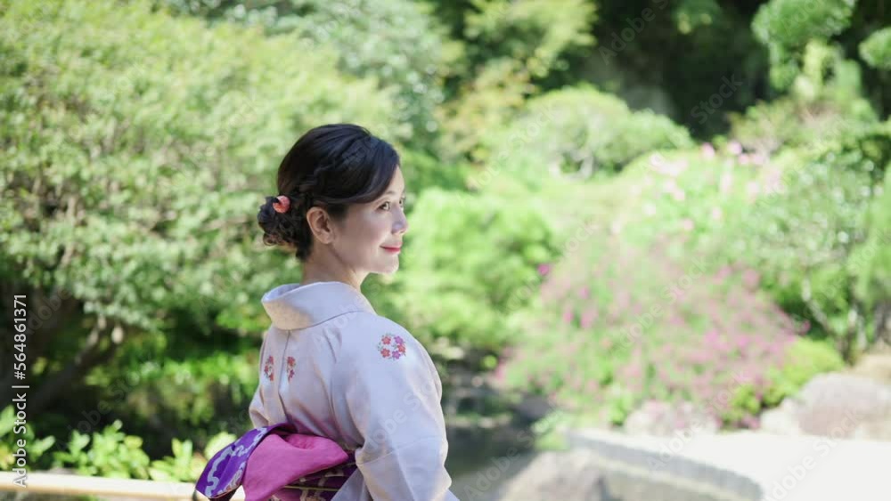 日本庭園の前で微笑む着物を着た上品な女性 日本庭園の前で微笑む着物を着た上品な女性