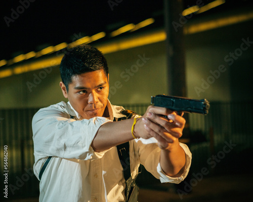 A man dressed as a detective / policeman aims his gun.